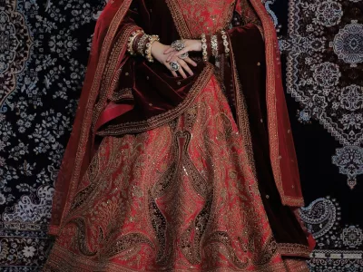 Bride in a deep red and maroon bridal lehenga with heavy embroidery and a maroon dupatta drawn over her head