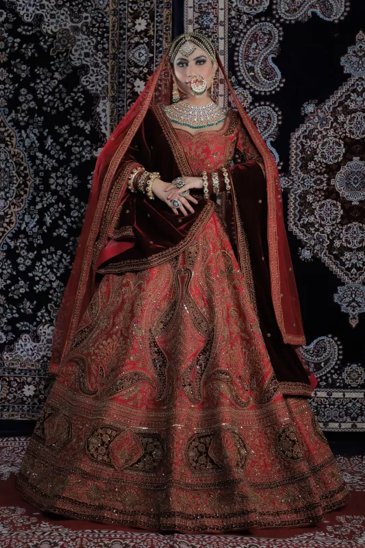 Bride in a deep red and maroon bridal lehenga with heavy embroidery and a maroon dupatta drawn over her head