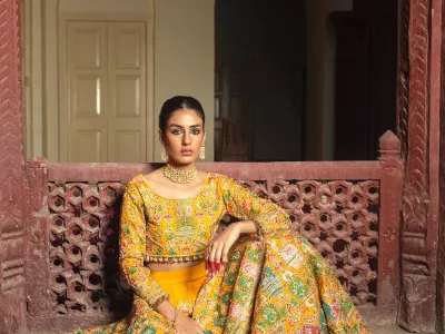 Woman in a mustard yellow multicolour printed lehenga standing in a haveli courtyard