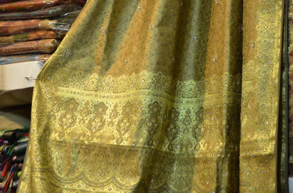 Close-up of gold Banarasi brocade fabric draped on display