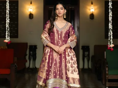 Woman in a maroon and gold brocade Anarkali-style kurta with a dupatta and purple churidar
