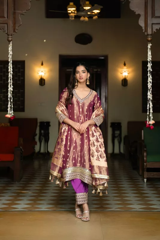 Woman in a maroon and gold brocade Anarkali-style kurta with a dupatta and purple churidar