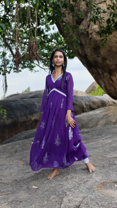 Woman in a purple flared floor-length Anarkali dress with white embroidery, outdoors