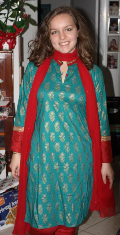 Woman in a teal and gold brocade kurta with a red dupatta
