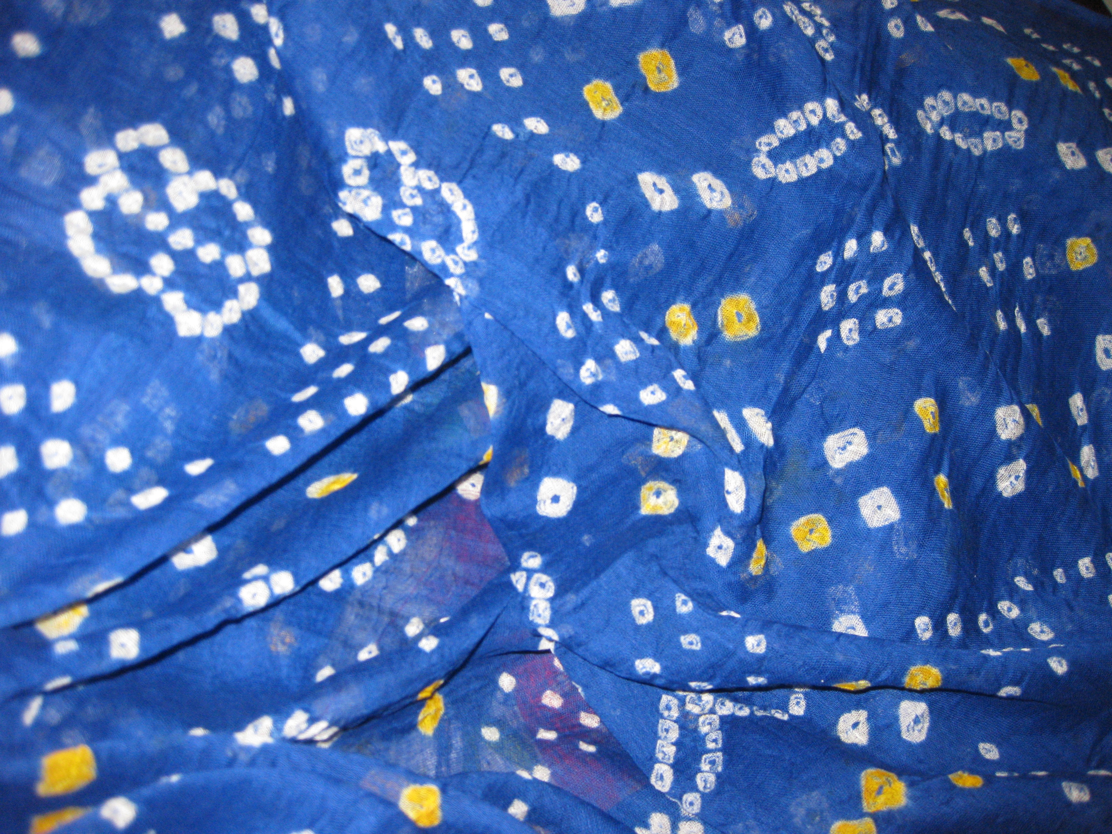Close-up of blue bandhani tie-dye fabric with yellow dots