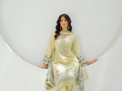 Woman in a pastel lemon embroidered straight suit with a matching dupatta, seated in a white studio arch